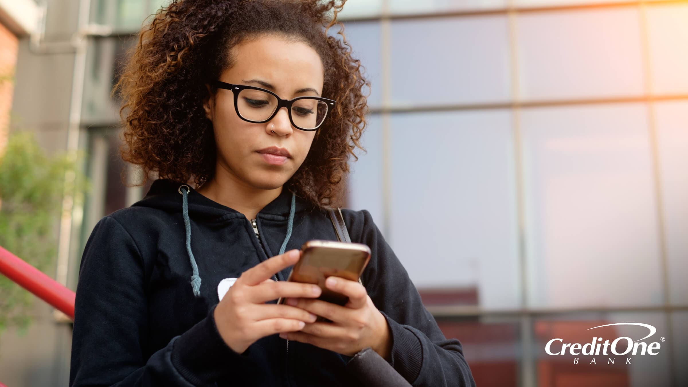 Woman on her phone checking the Credit One Bank mobile app